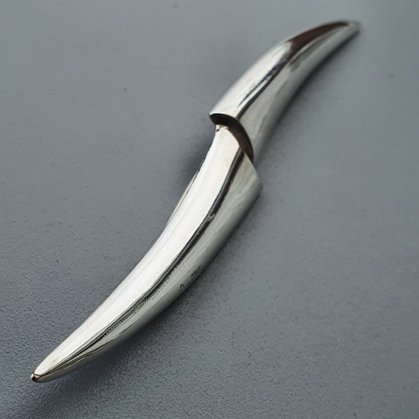 Curved, metallic blade or knife with a sleek, modern design.