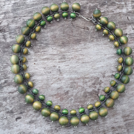 Circular necklace made of matte green beads strung on a thin wire.