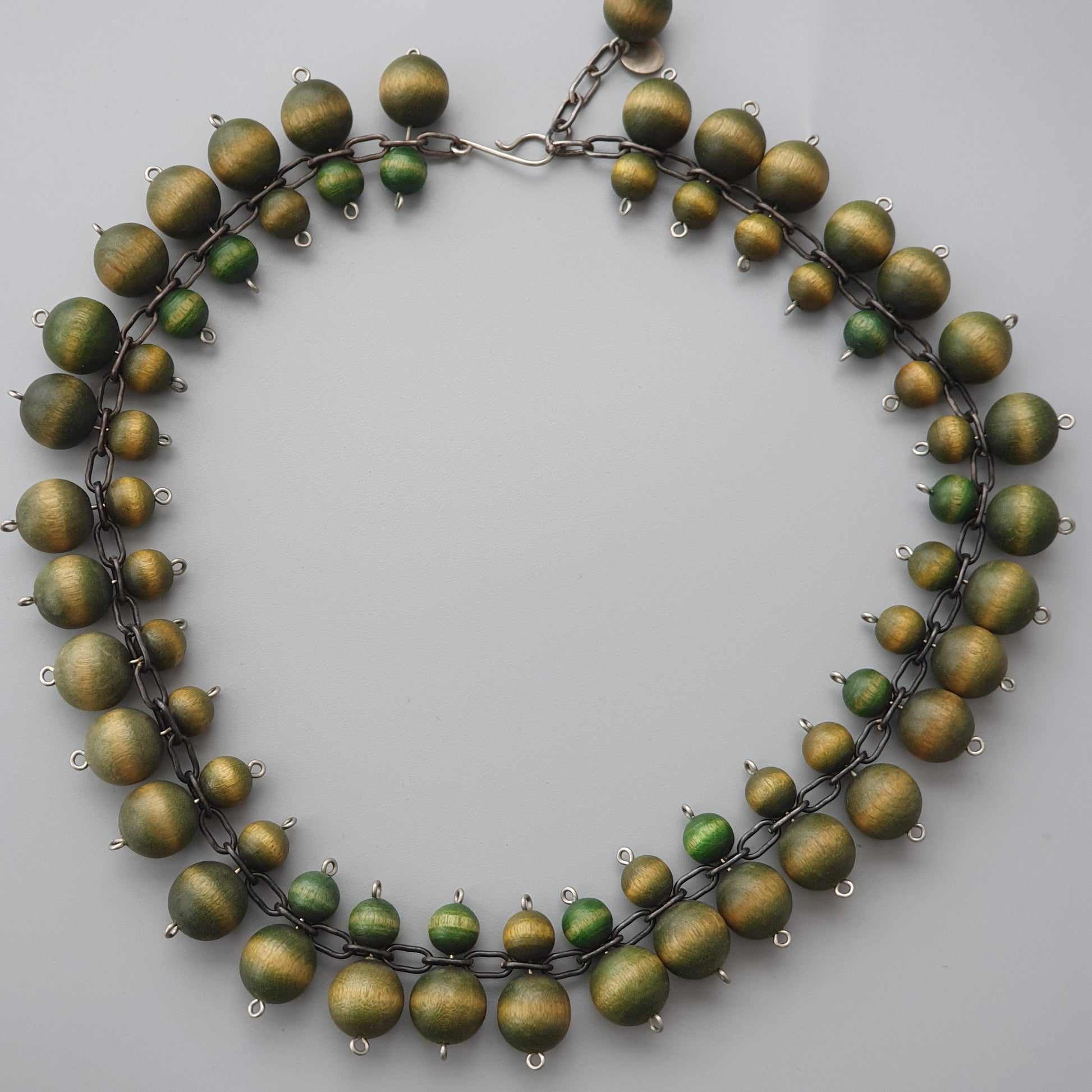 Necklace made of matte green and gold beads arranged in a circular pattern.