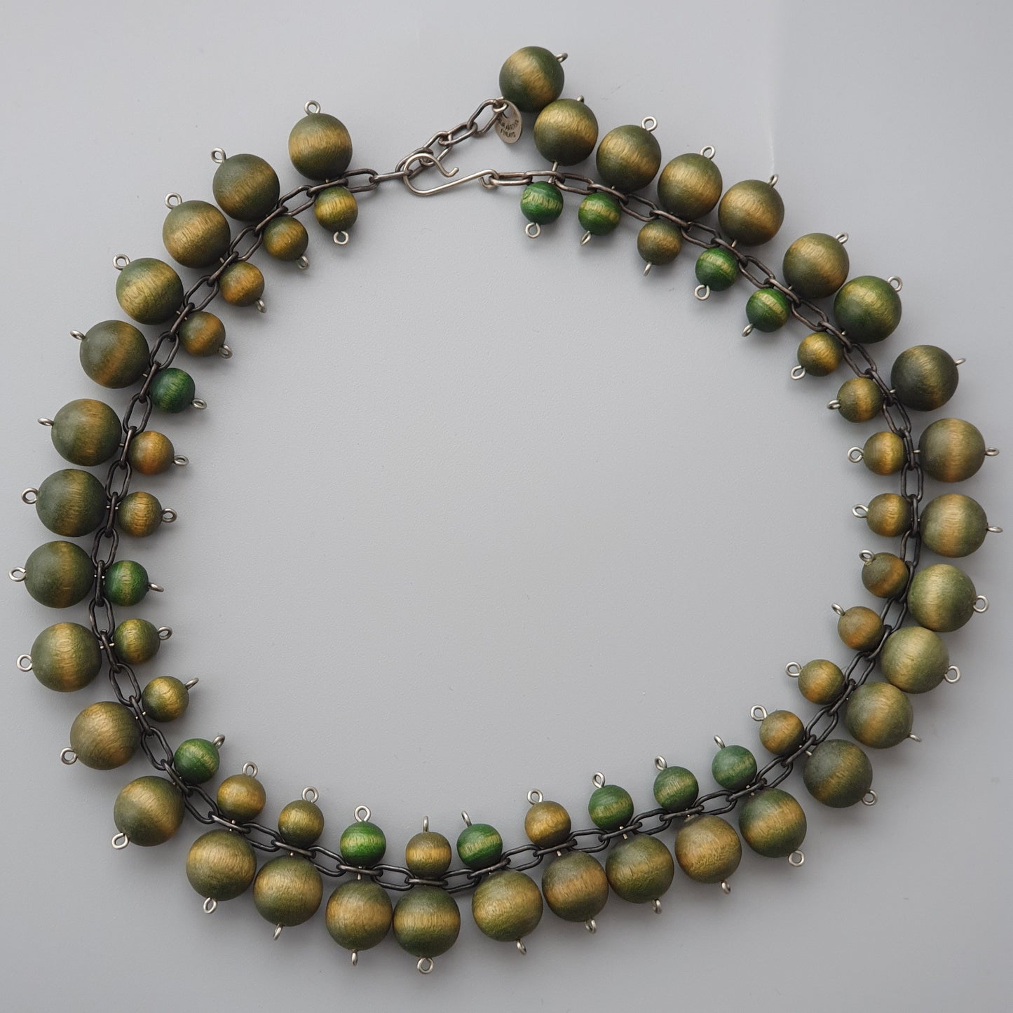 Necklace made of matte gold-colored beads with small green accents.