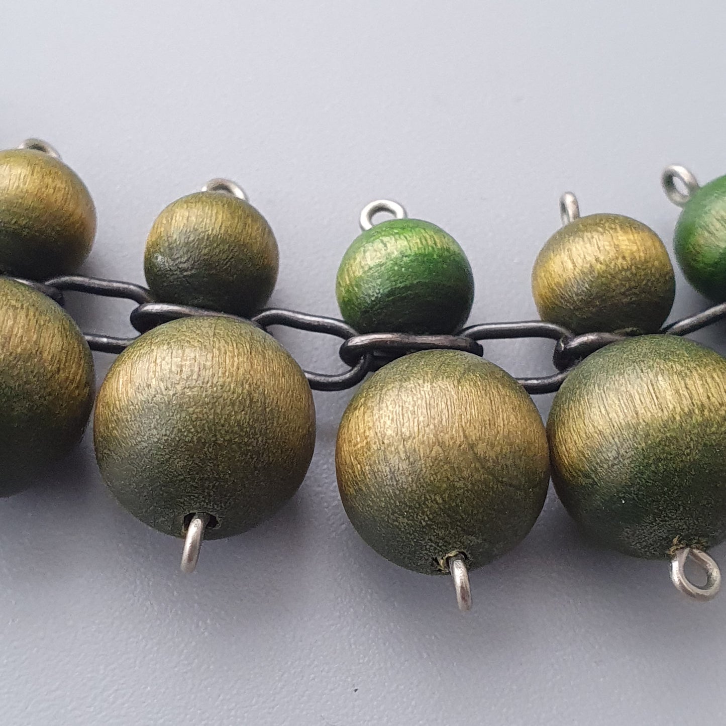 Metallic beads in shades of gold and green strung on a chain.