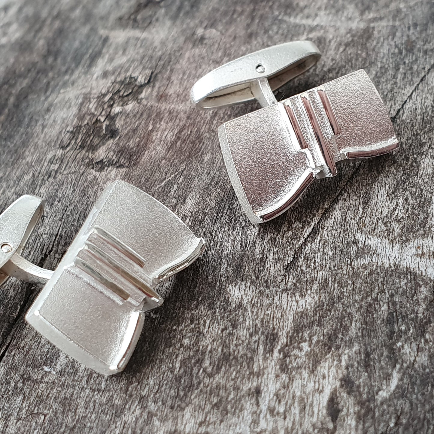 Pair of silver cufflinks with a geometric design.