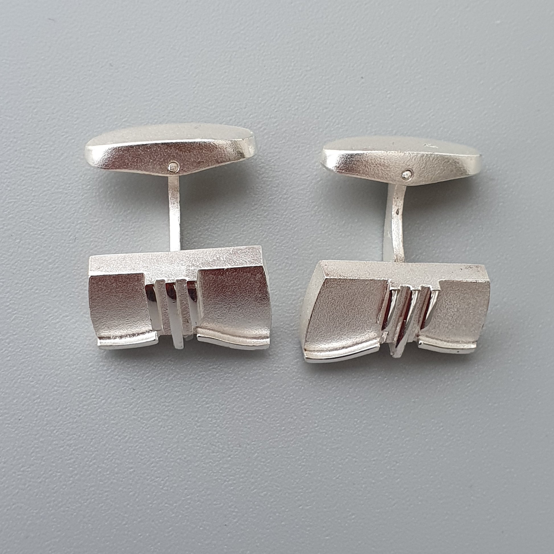 Pair of silver cufflinks with geometric designs.