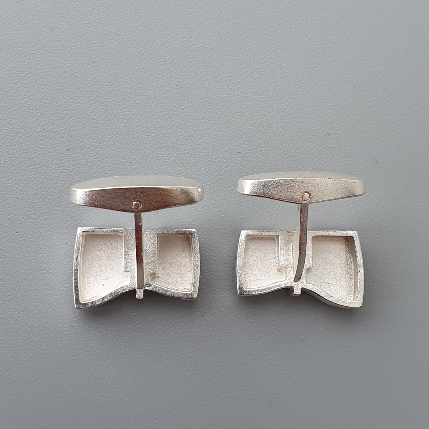 Pair of silver cufflinks with bow-shaped designs.