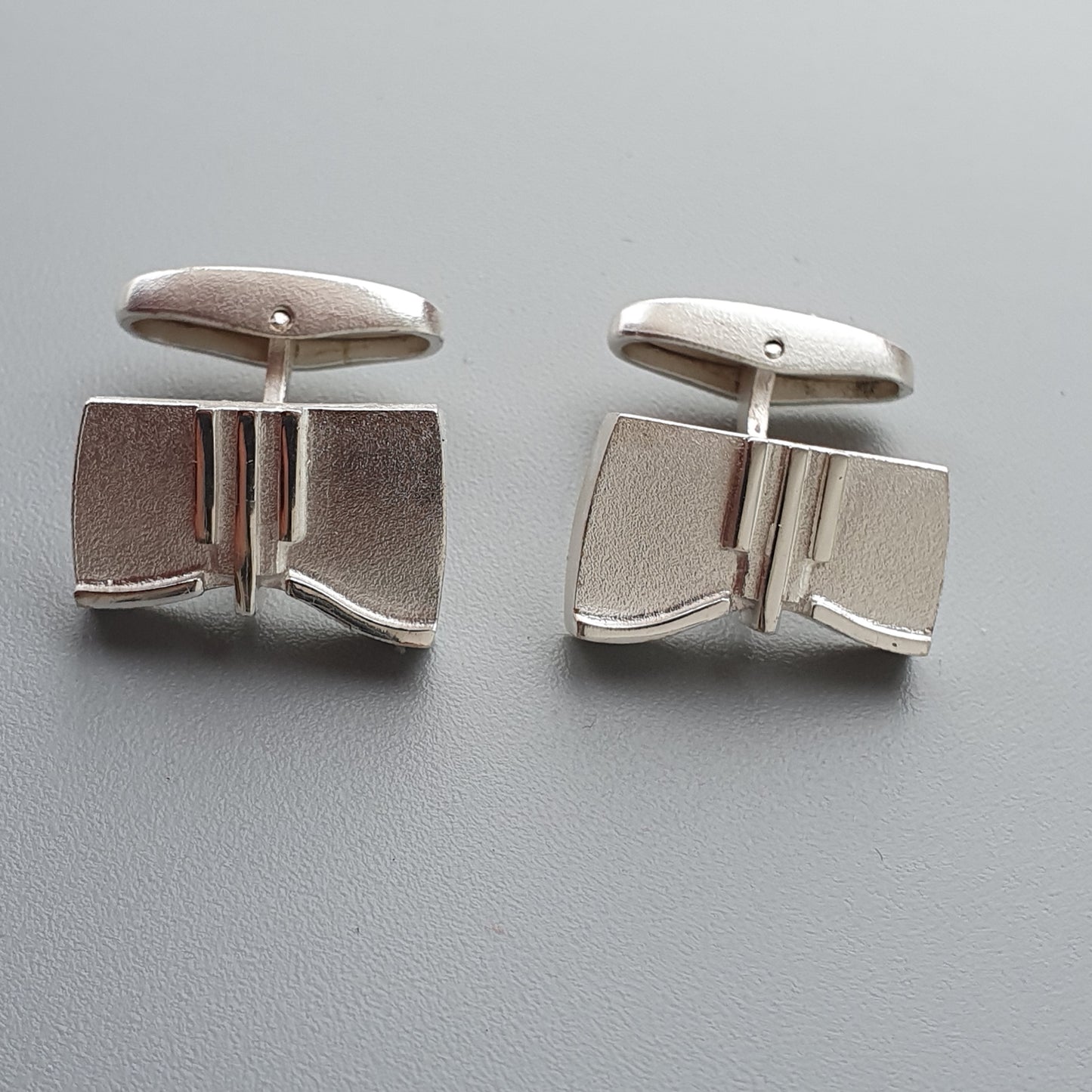 Pair of silver cufflinks with a geometric, angular design.