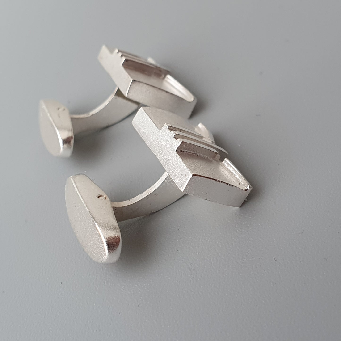 Pair of silver cufflinks with a modern geometric design.