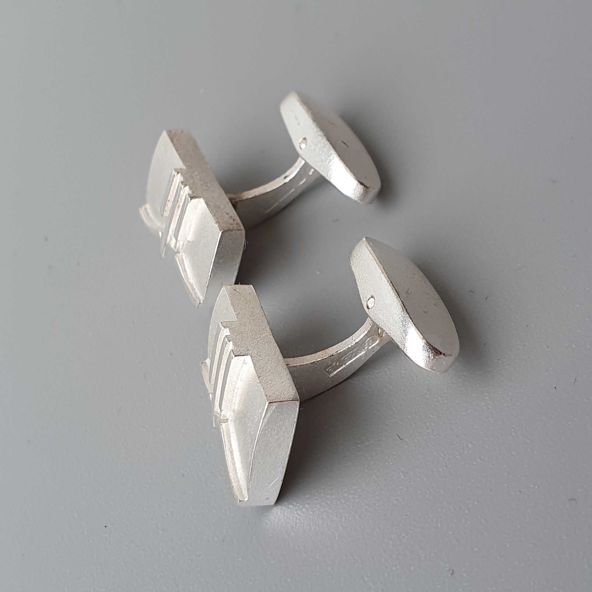 Pair of white rectangular cufflinks with ridged edges.