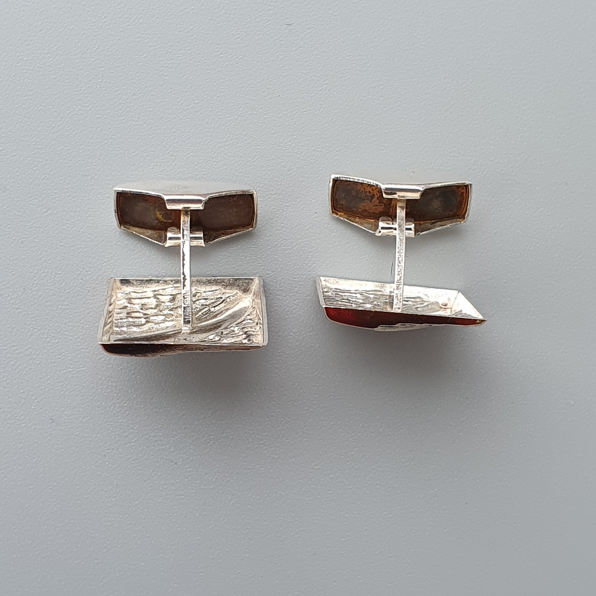 Pair of silver cufflinks with rectangular designs and brown accents.