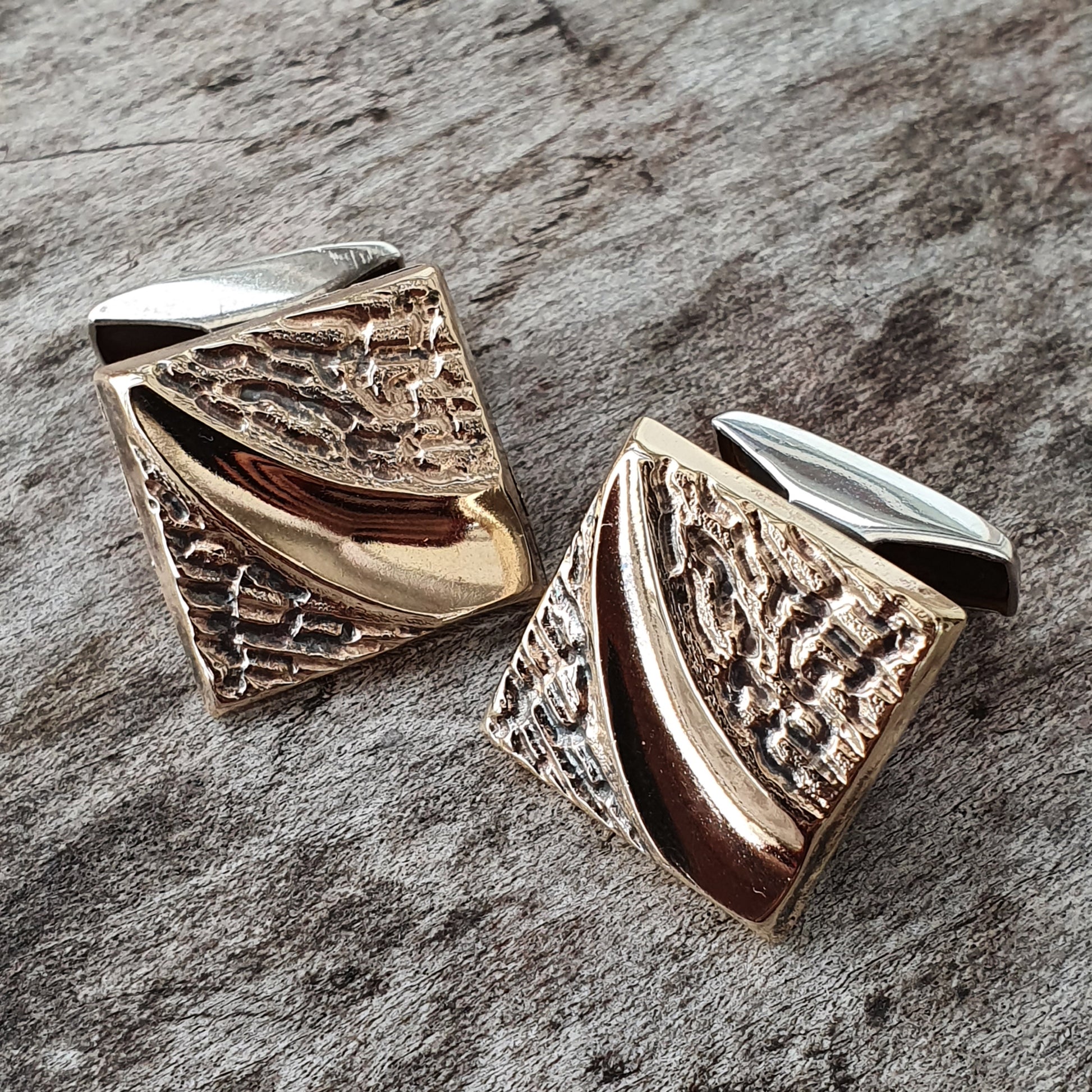 Pair of ornate gold and silver cufflinks with textured geometric designs.