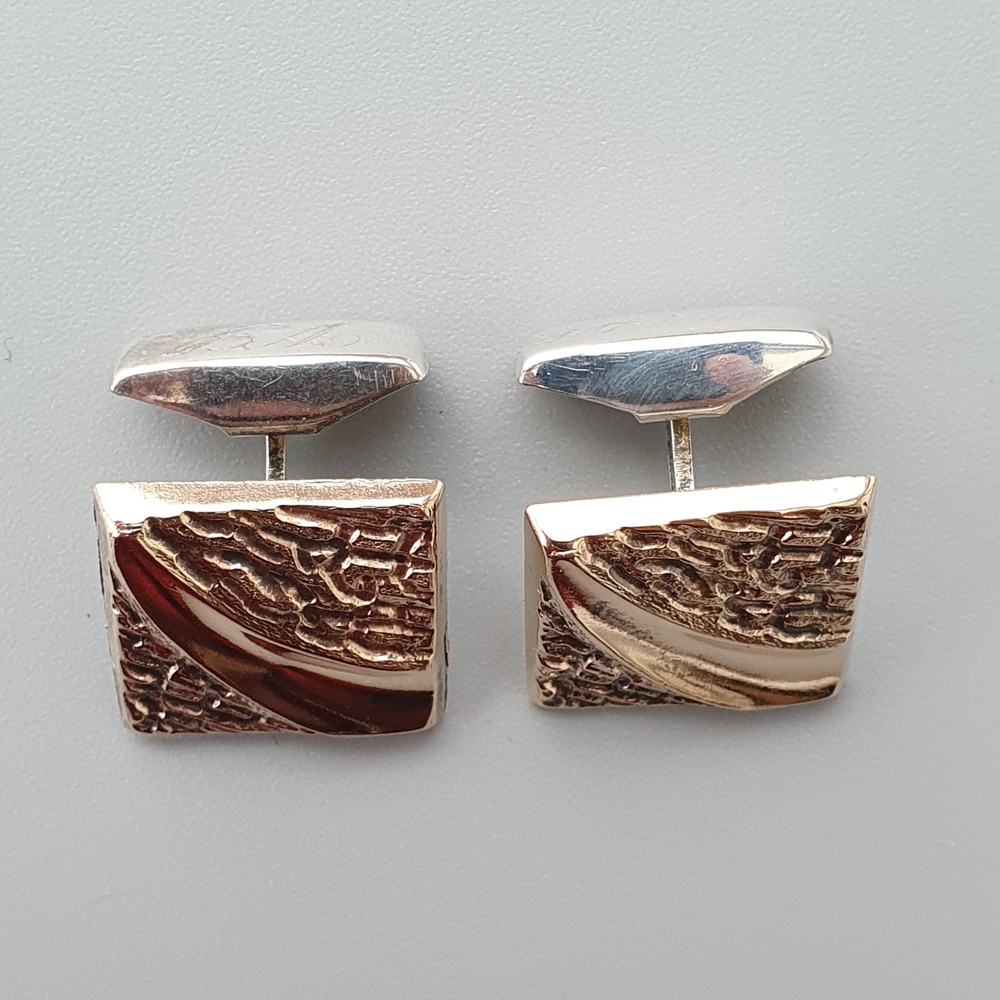 Pair of rectangular silver and bronze cufflinks with textured patterns.