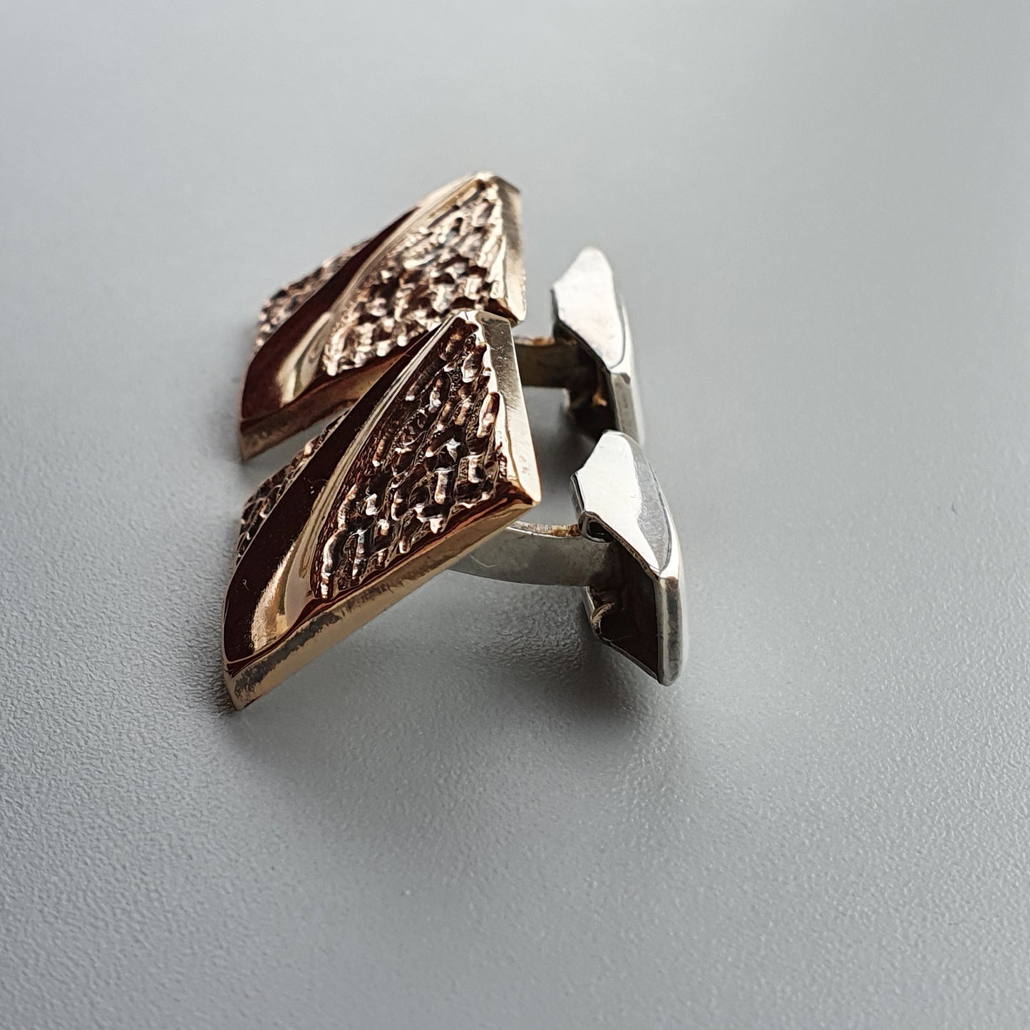 Pair of ornate cufflinks with a triangular design and textured surface.