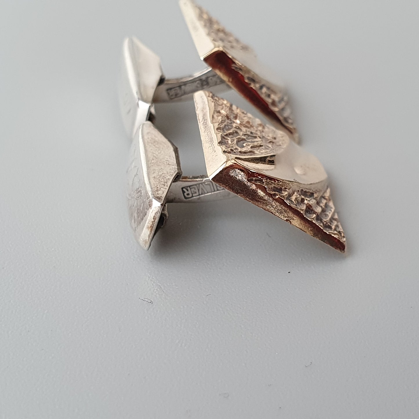 Pair of silver-toned cufflinks with triangular geometric designs.