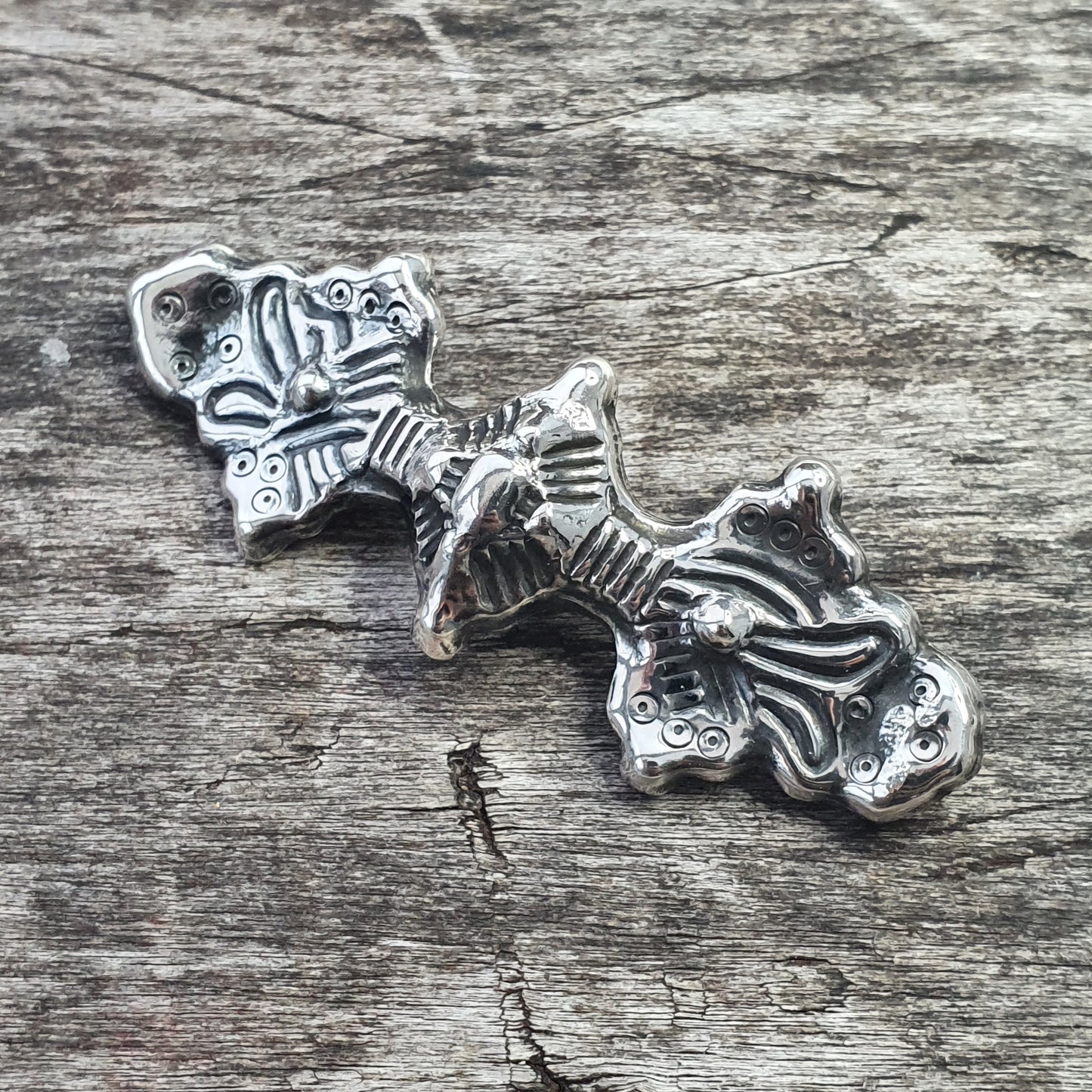 Silver pendant or charm shaped like a stylized fish skeleton with decorative patterns.