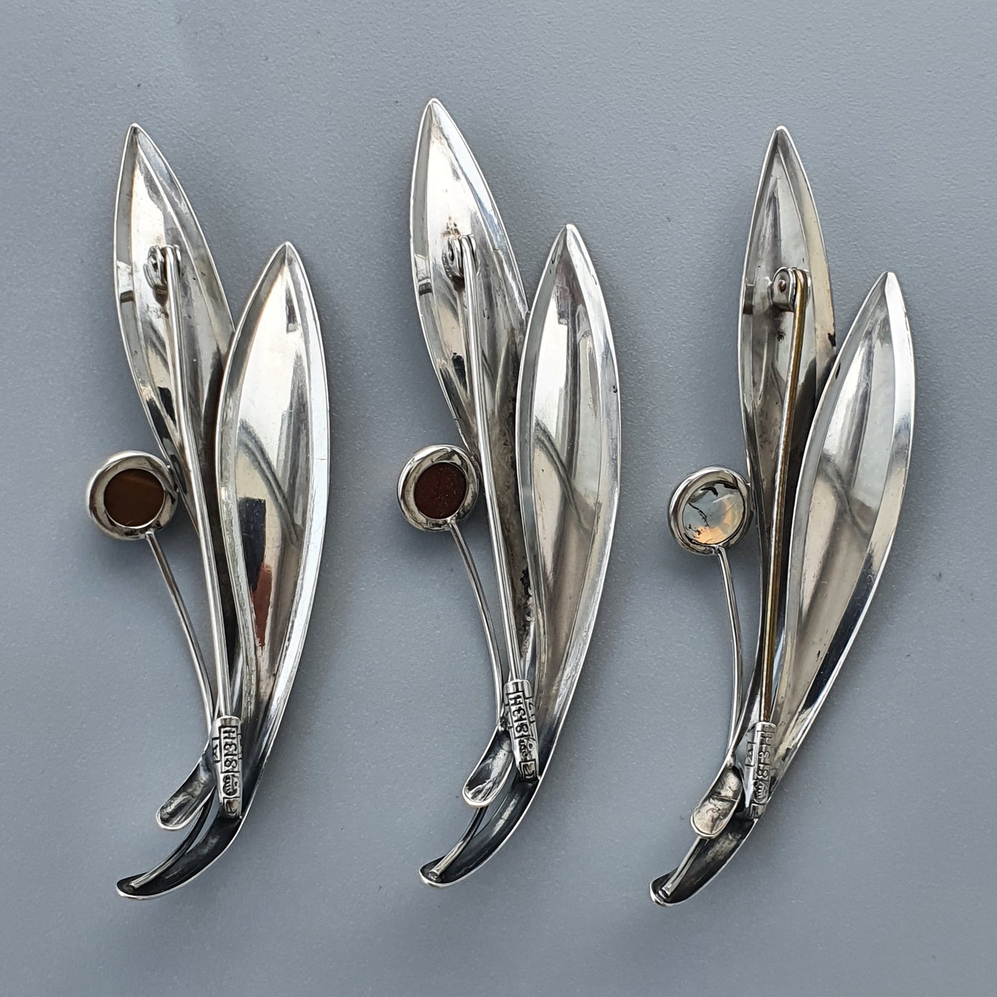 Silver leaf-shaped brooches with gemstone accents.