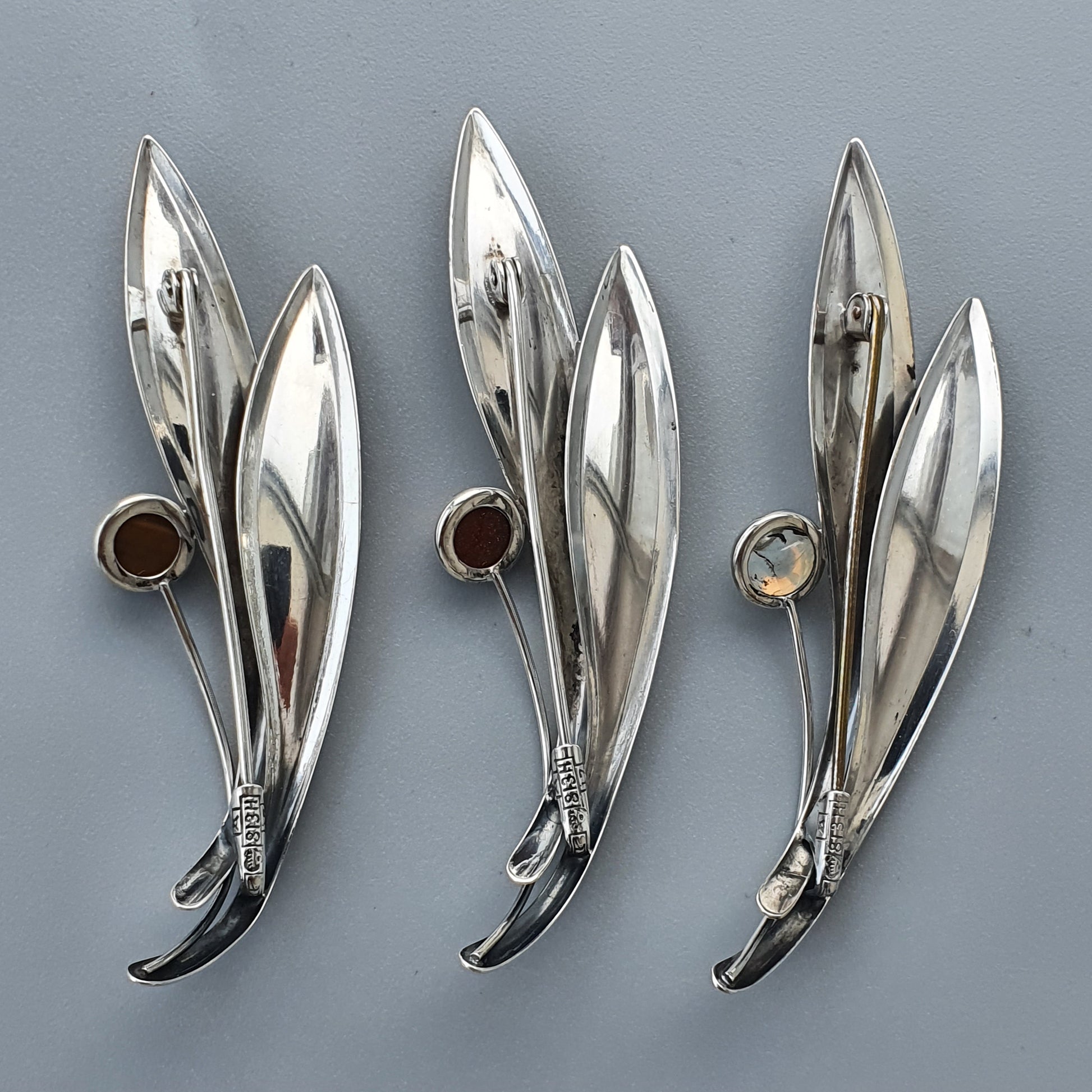 Silver leaf-shaped brooches with gemstone accents.