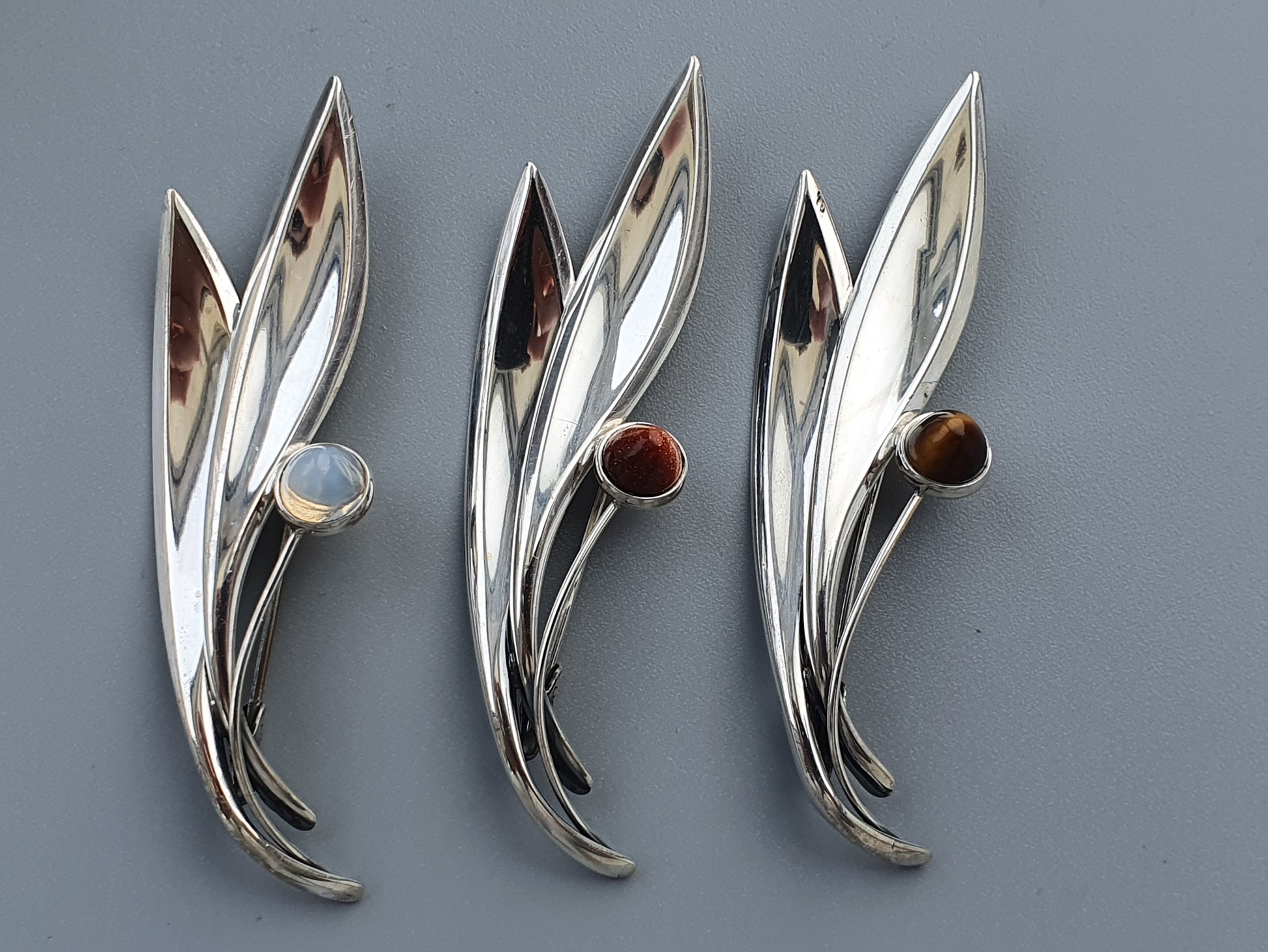 Silver leaf-shaped brooches with gemstone accents.