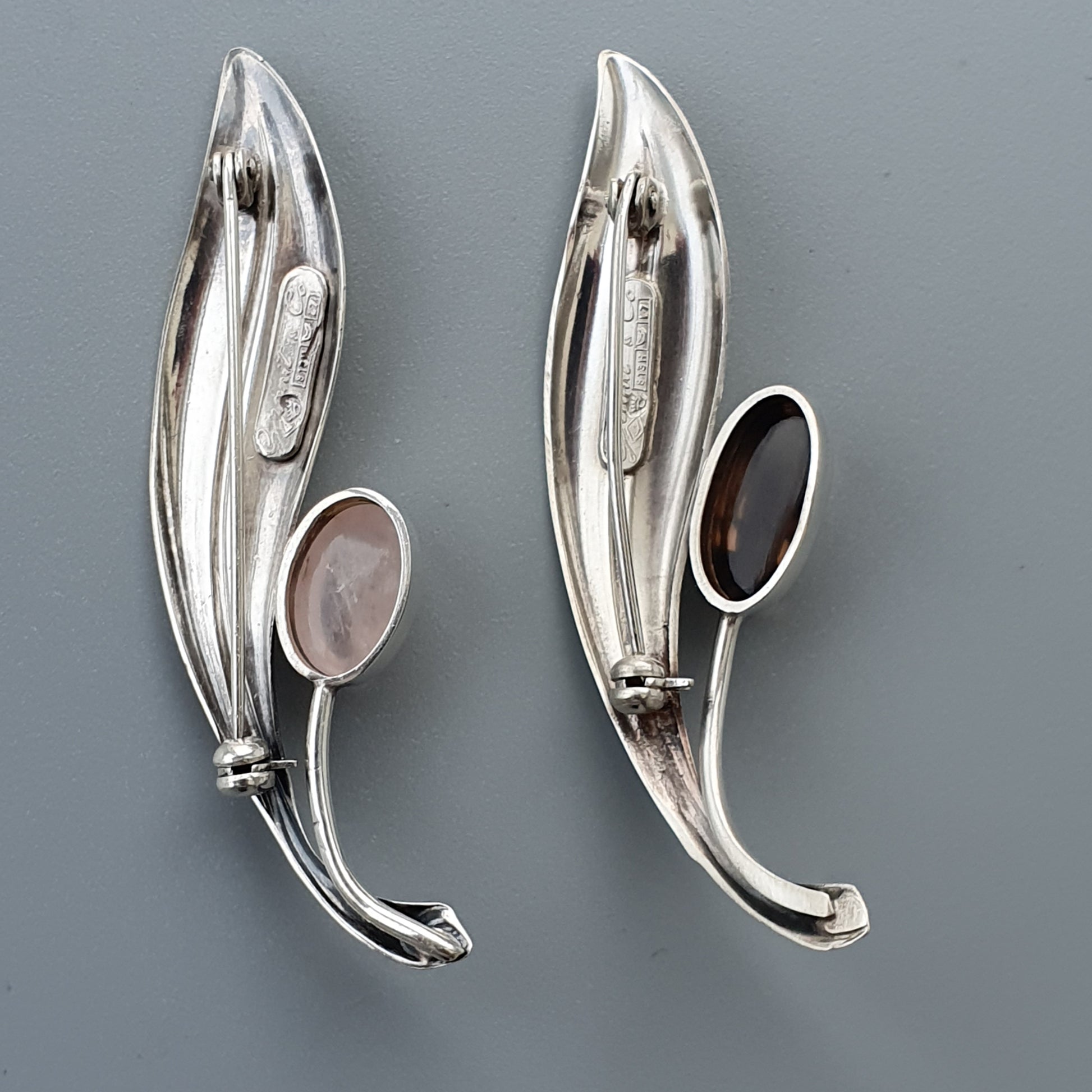 Pair of sleek, silver earrings with oval gemstone accents in an elongated leaf-like design.