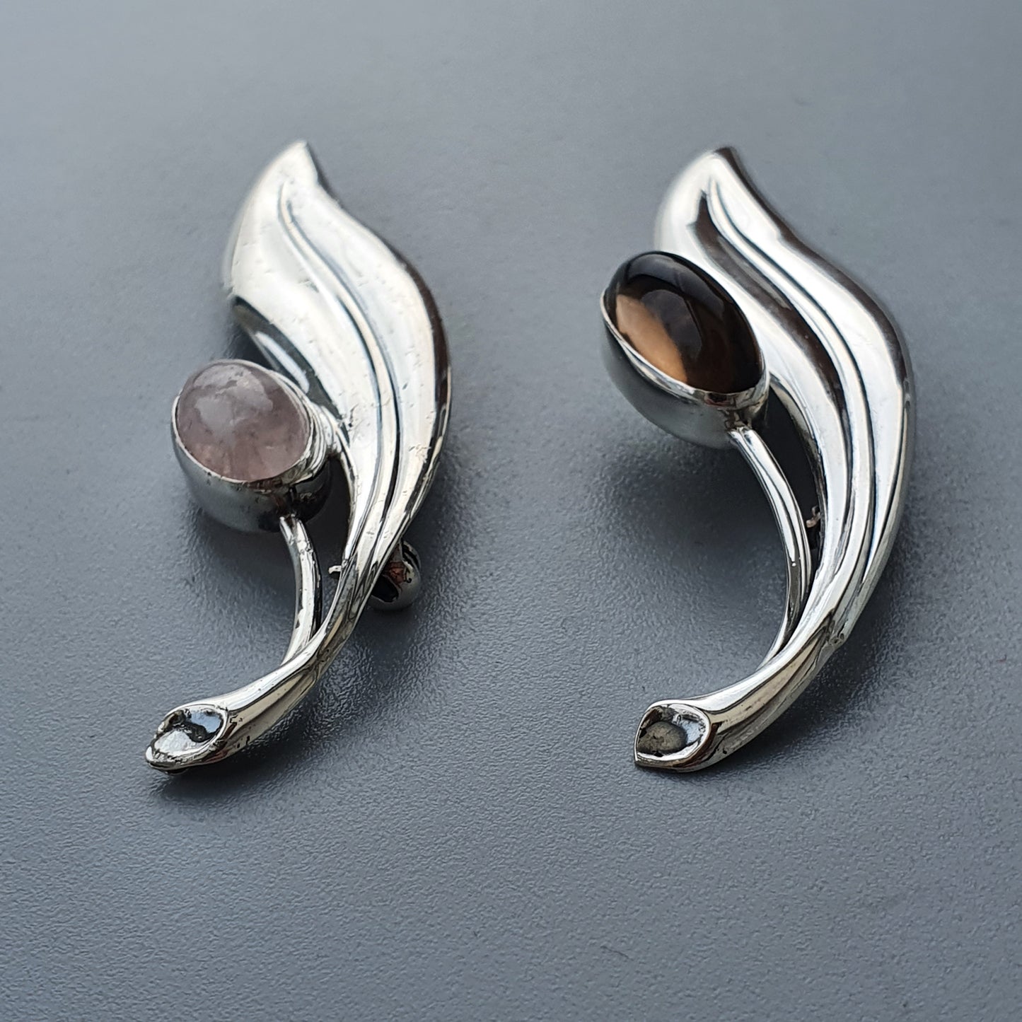 Pair of silver leaf-shaped earrings with gemstone accents.