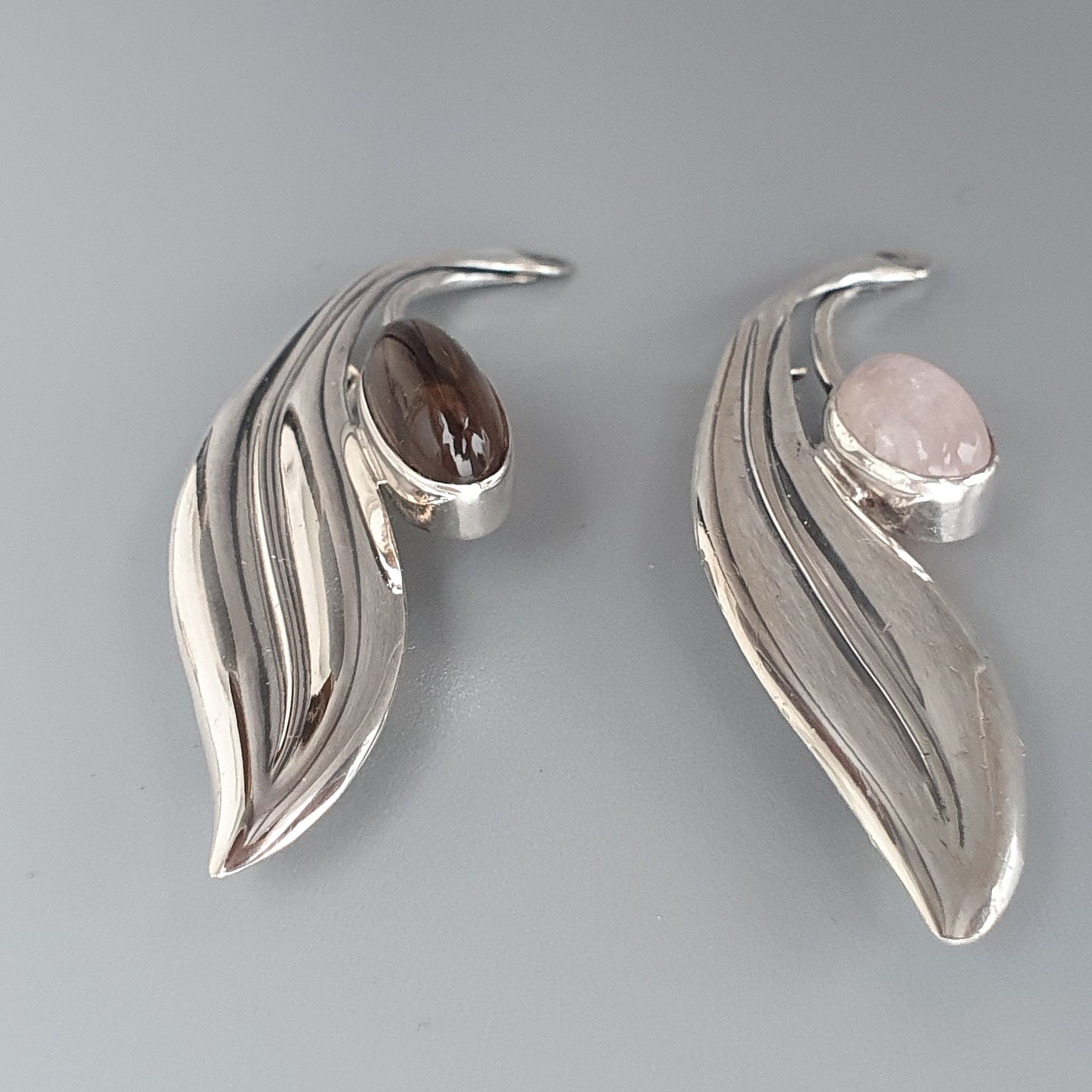 Pair of silver leaf-shaped earrings with gemstone accents.