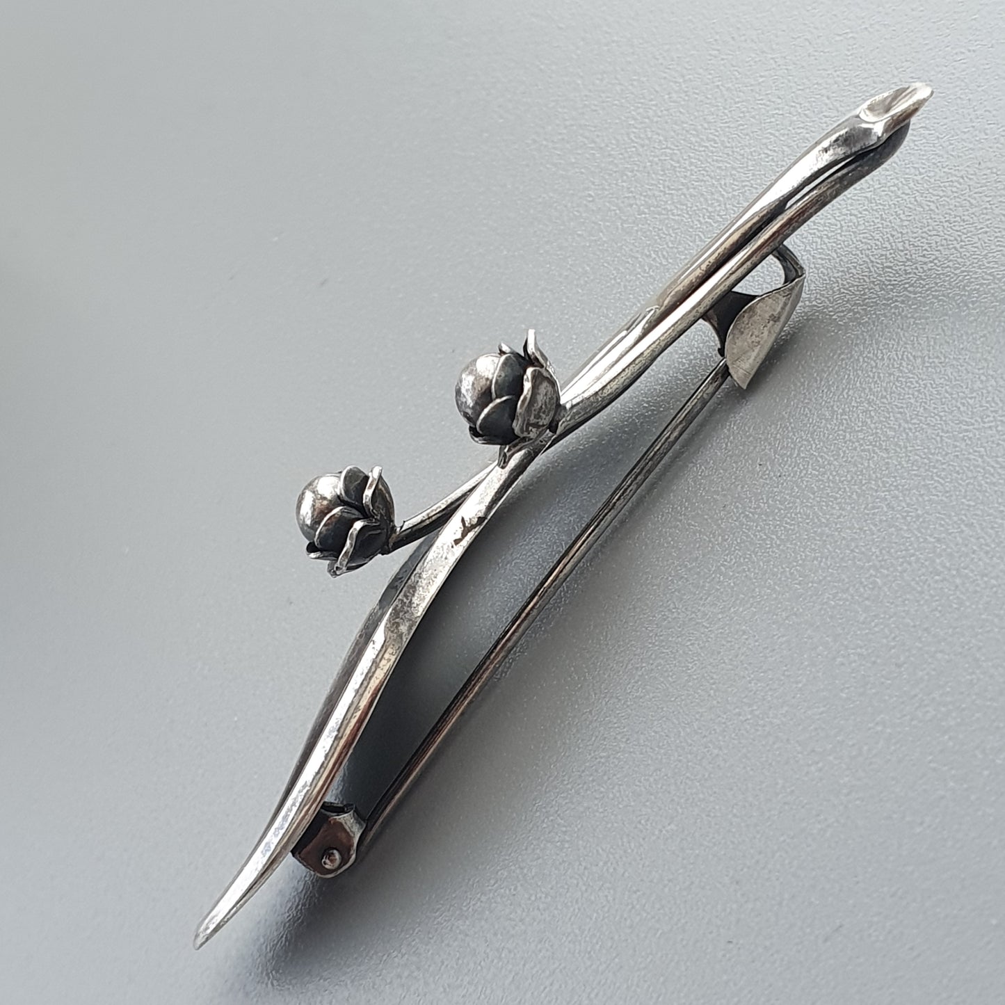 Silver brooch or pin shaped like a branch with flower buds.