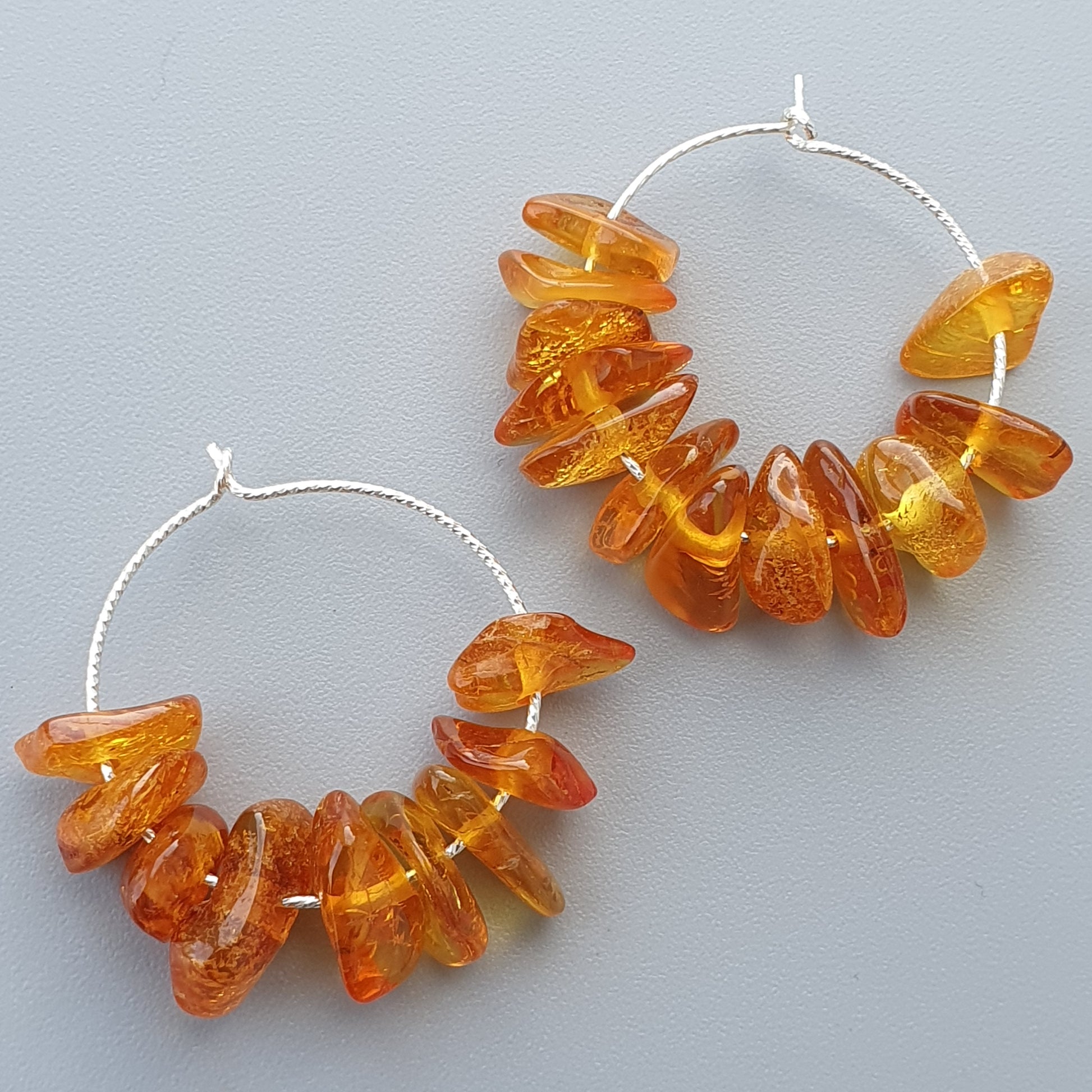 Pair of hoop earrings adorned with amber-colored stone beads.