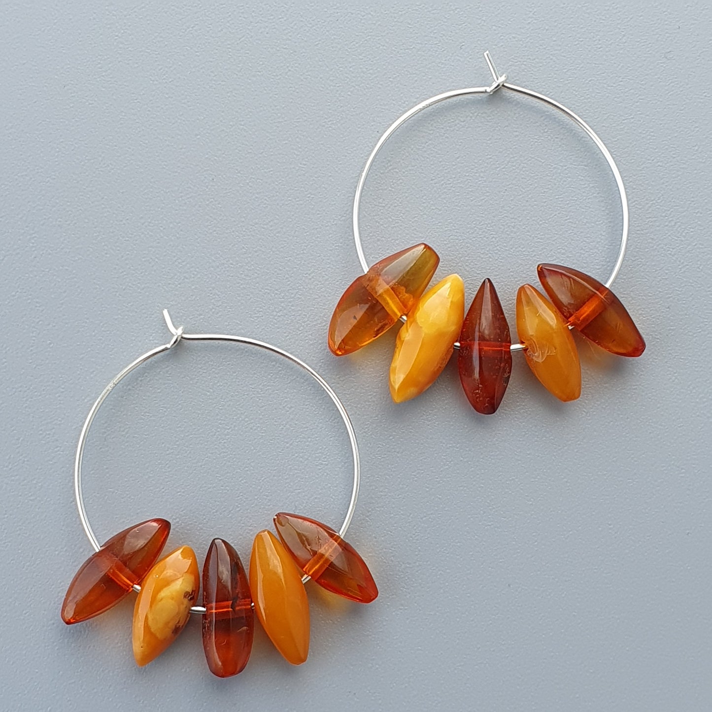 Hoop earrings adorned with amber-colored beads in various shades.