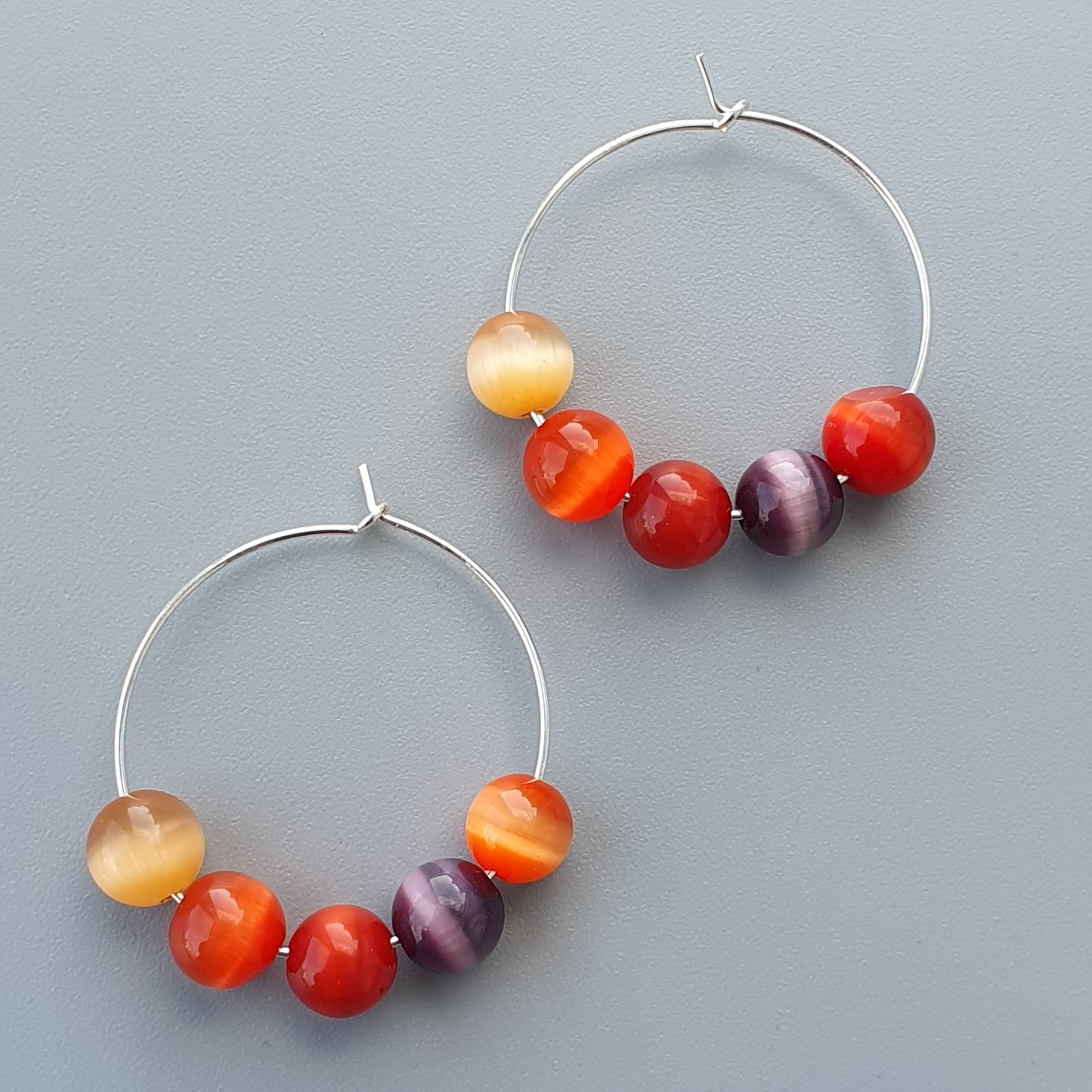 Pair of hoop earrings with colorful beads strung on them.