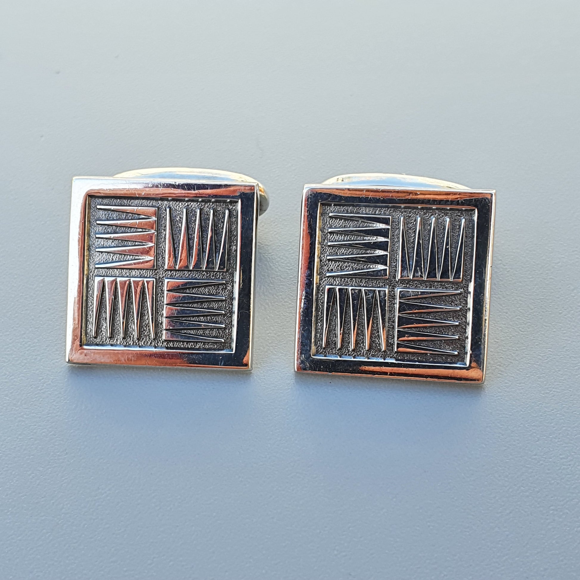 Pair of square metal cufflinks with an etched geometric pattern.