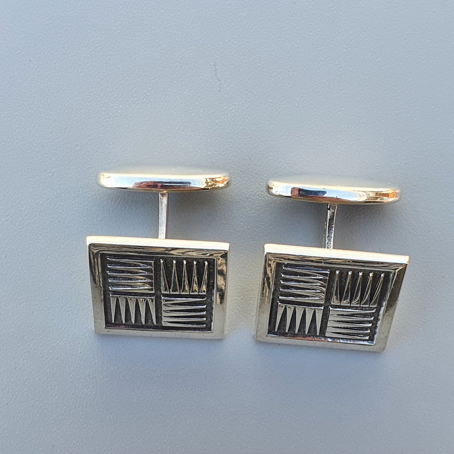 Pair of rectangular silver cufflinks with geometric etched patterns.