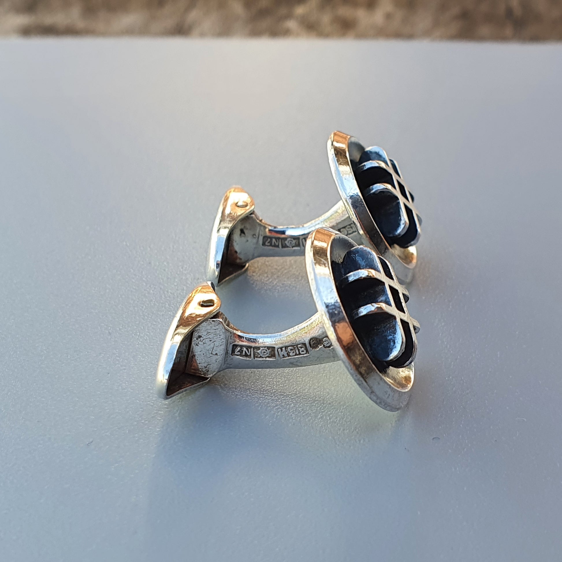 Pair of silver cufflinks with black inlaid designs.