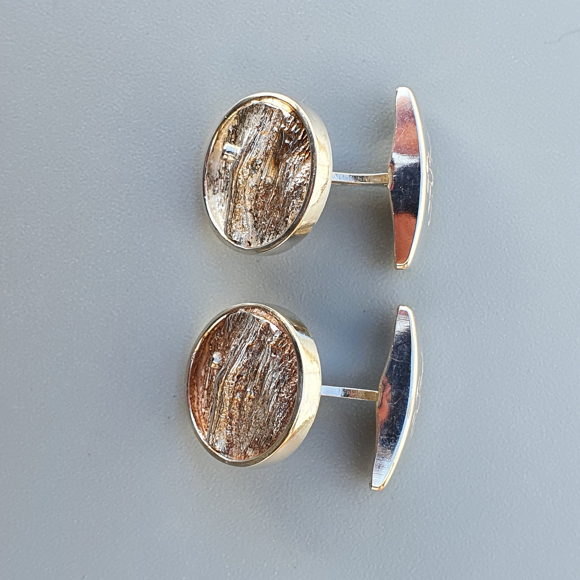 Pair of oval cufflinks with textured, wood-like centers set in silver-toned metal frames.