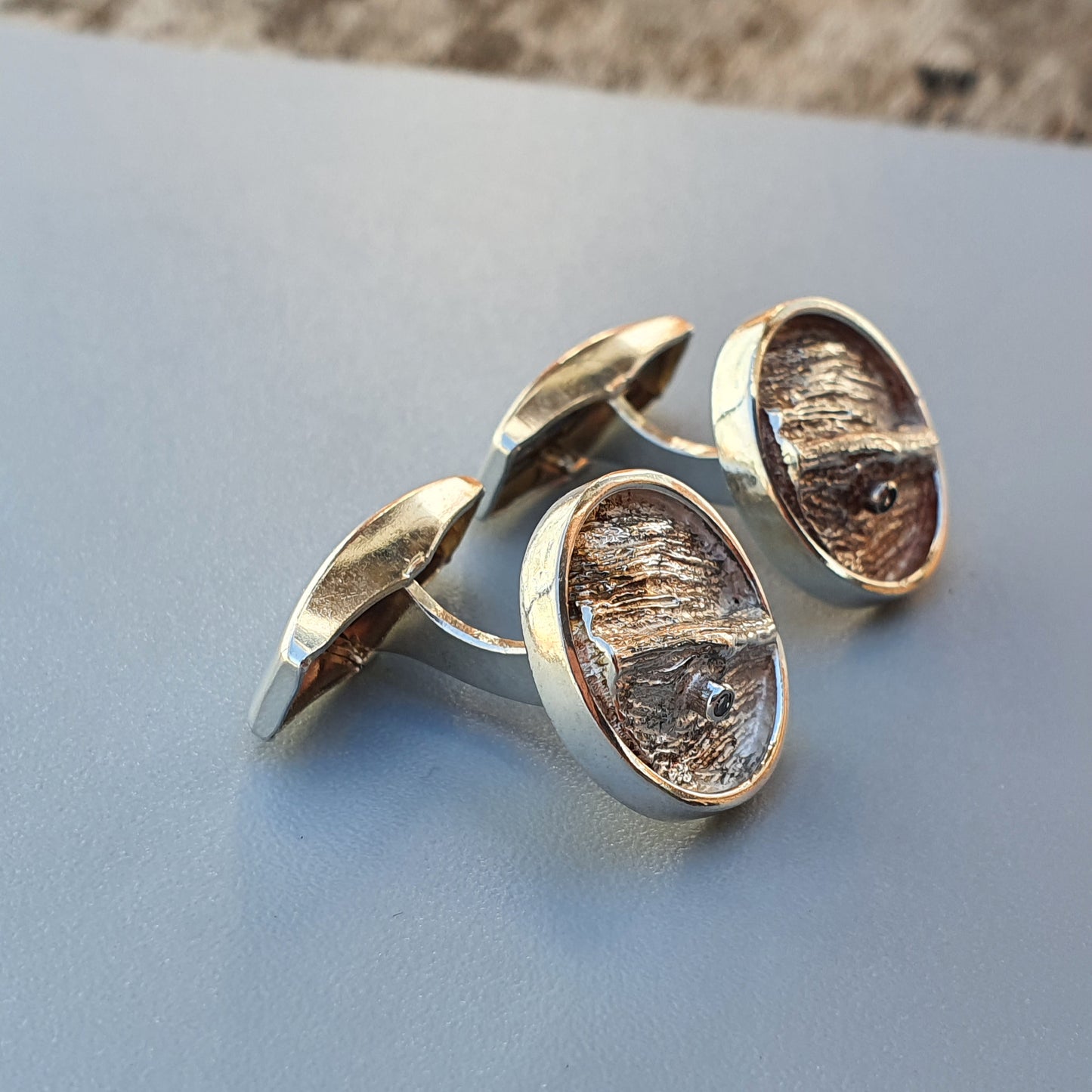 Pair of oval-shaped silver cufflinks with textured interior surfaces.