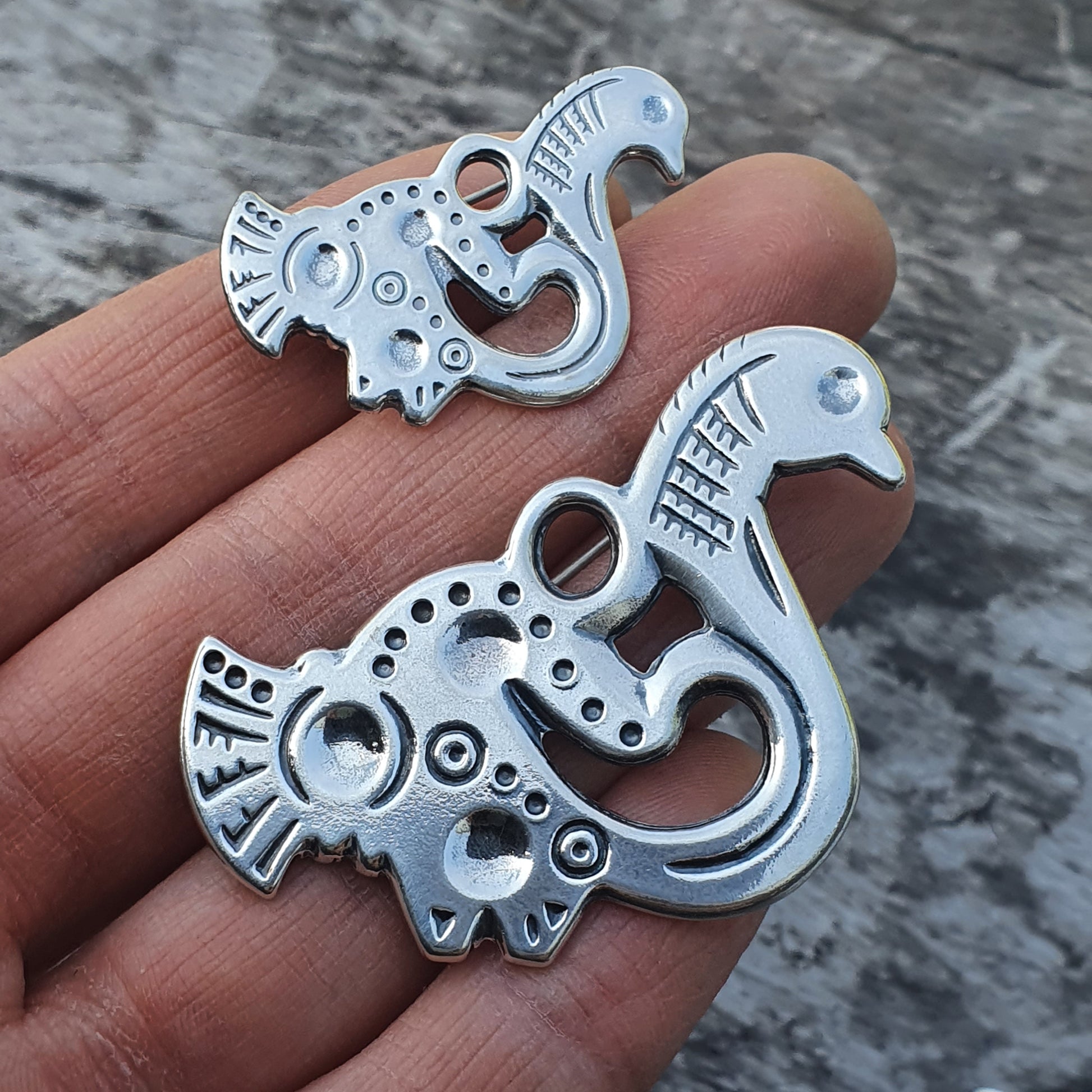 Ornate metal pendants or charms shaped like stylized birds or mythical creatures.