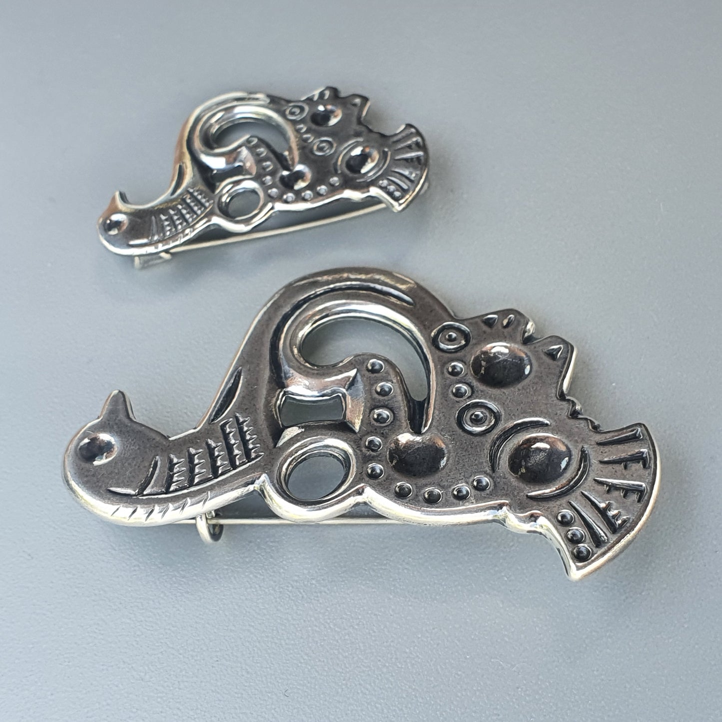 Ornate silver brooches or pendants shaped like stylized animals with intricate designs.