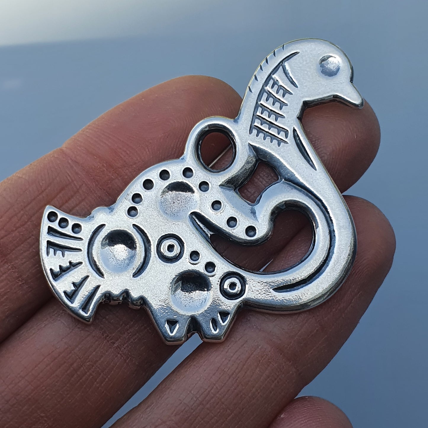 Stylized silver pendant or charm shaped like an abstract bird or mythical creature.