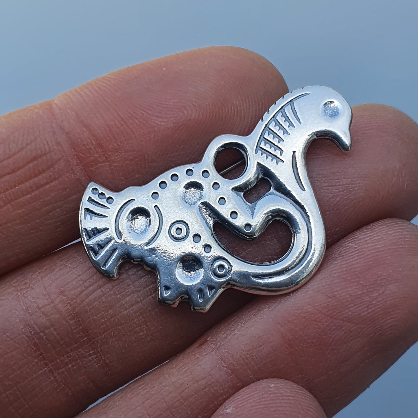 Ornate silver pendant shaped like a stylized bird or mythical creature.