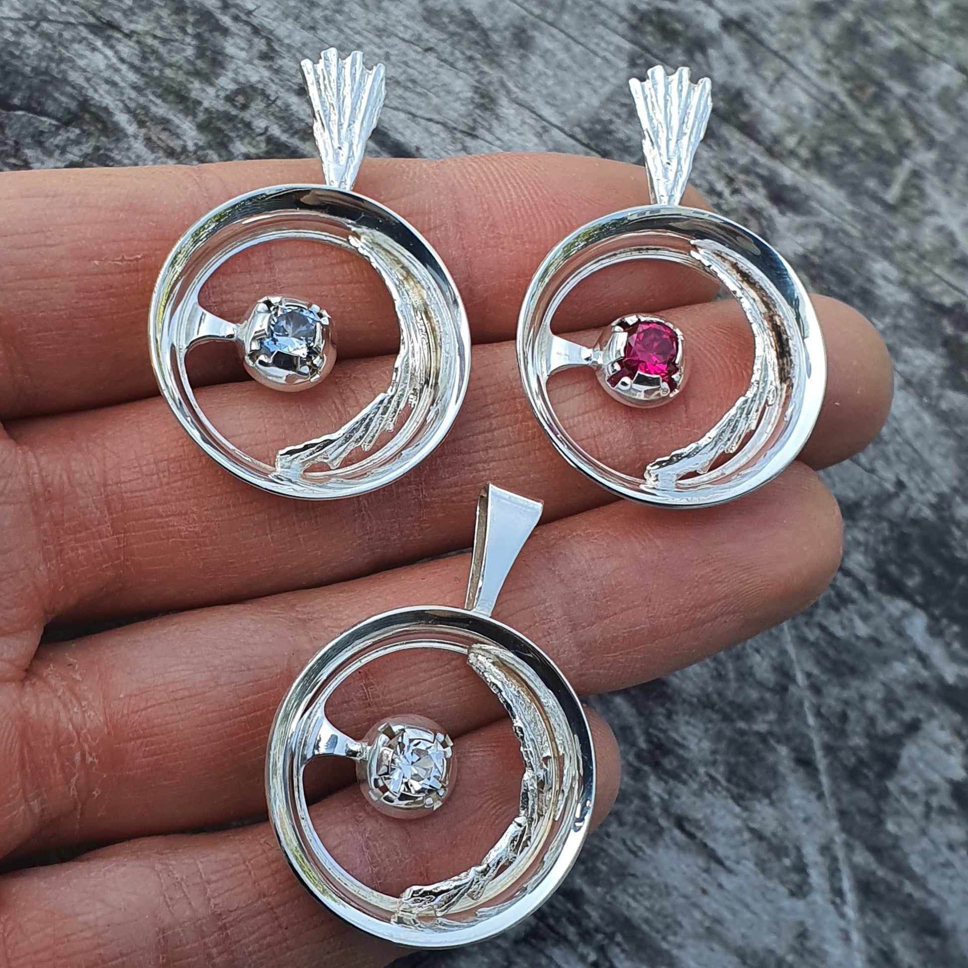 Silver circular pendants with gemstones set in the center.