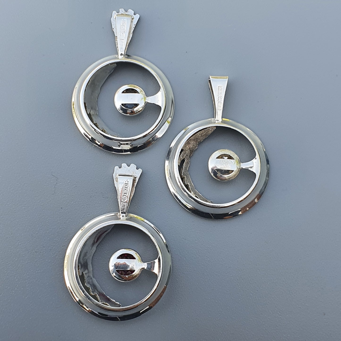 Silver circular pendants with spherical centers suspended within open rings.