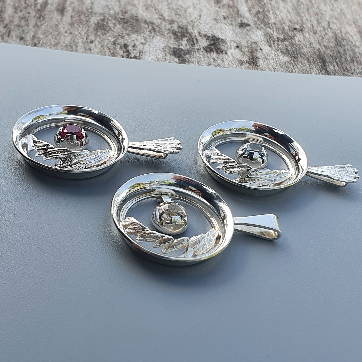 Silver-colored decorative dishes or trays with handle-like extensions and small gemstones in the centers.