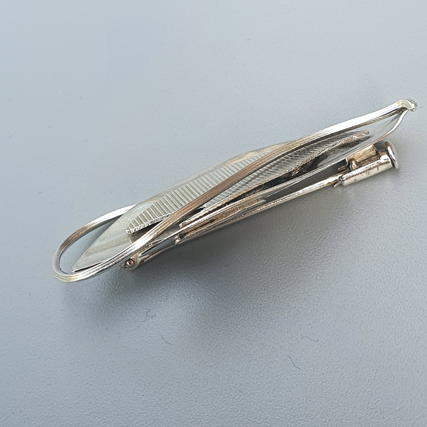 Silver-toned metal hair clip with a textured surface and spring mechanism.