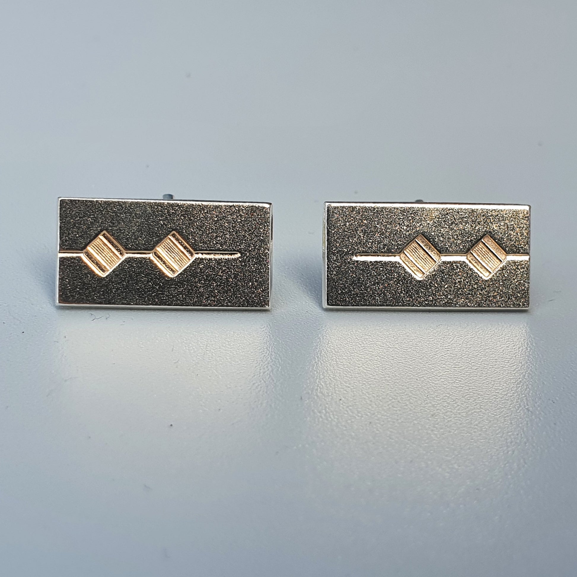 Pair of rectangular silver cufflinks with gold diamond-shaped accents.