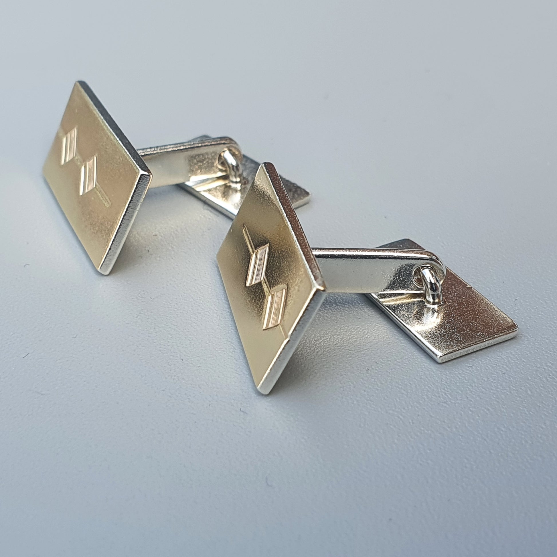 Pair of silver cufflinks with square-shaped faces and engraved designs.