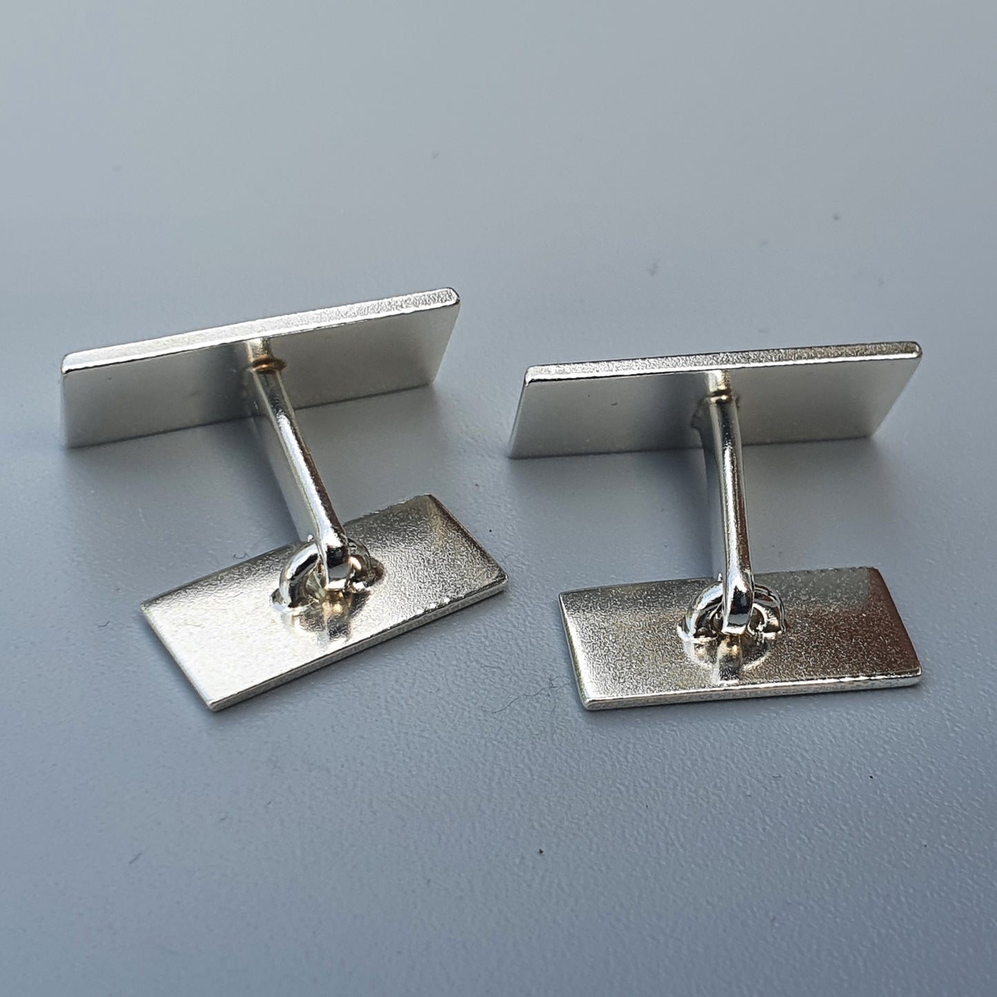 Pair of silver-colored rectangular cufflinks with T-bar fasteners.