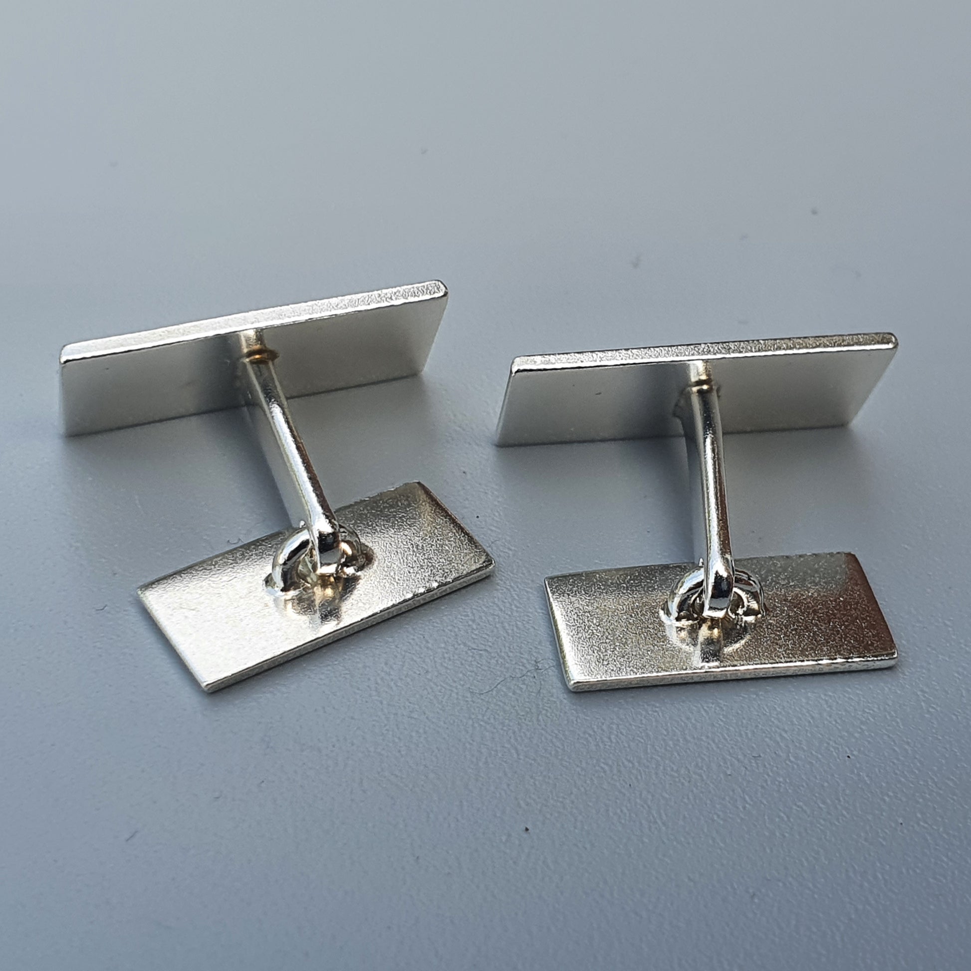 Pair of silver-colored rectangular cufflinks with T-bar fasteners.