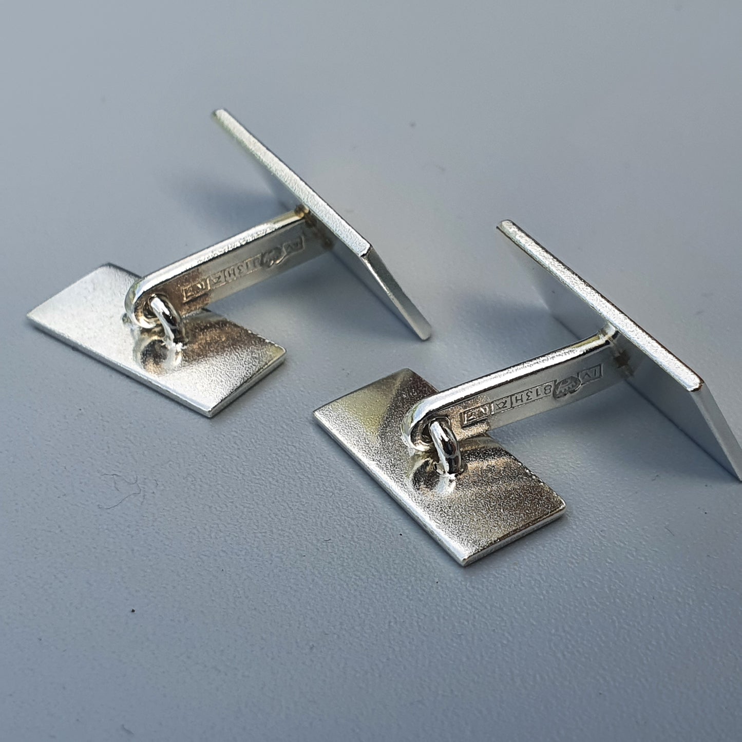 Pair of silver cufflinks with rectangular bases and T-shaped bars.