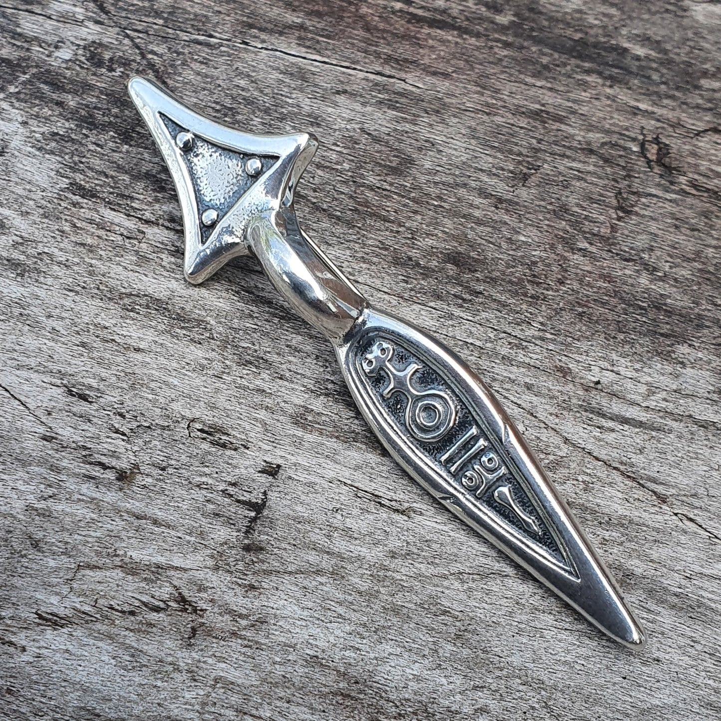 Silver arrow-shaped pendant or charm with ’LOVE’ engraved on its shaft.