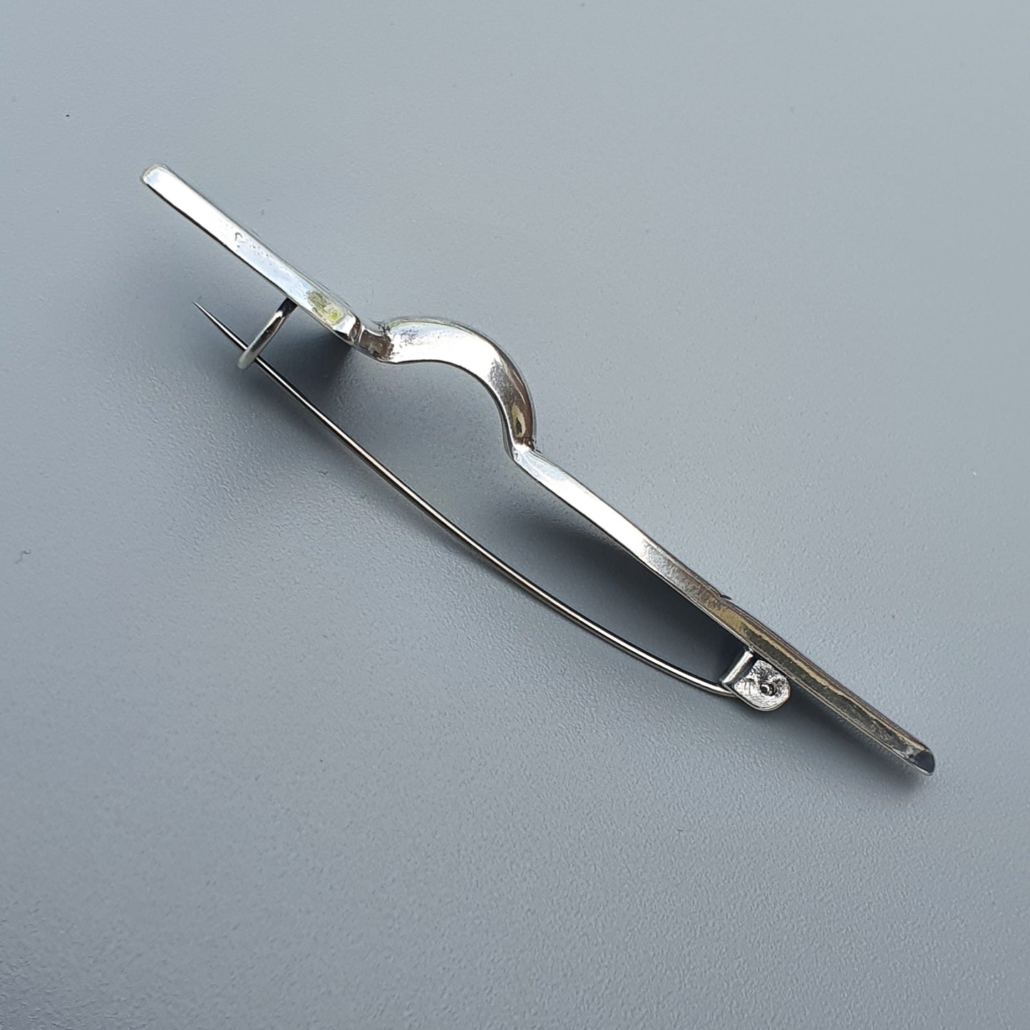 Metallic compass or drafting tool with adjustable arms and a pencil holder.