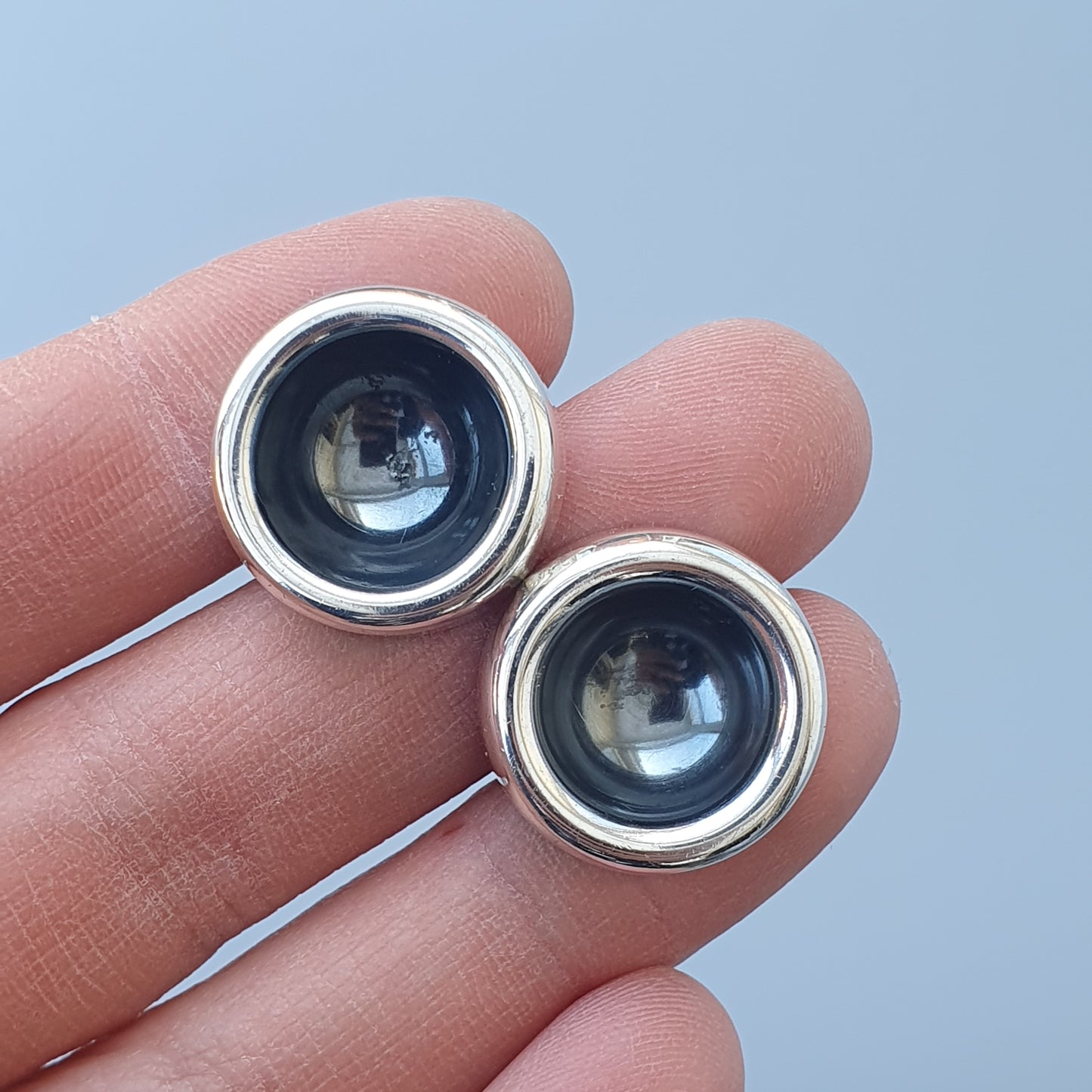 Two circular camera lenses or optical elements held between fingertips.