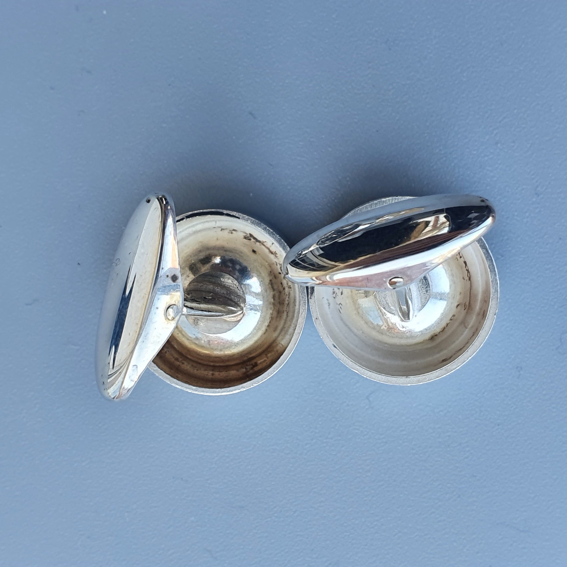 Silver cufflinks with hinged circular designs.