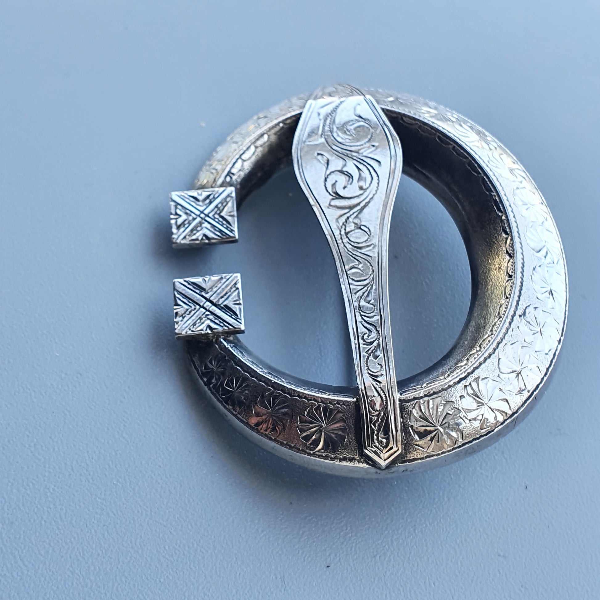 Silver Celtic-style penannular brooch with intricate engraved designs.